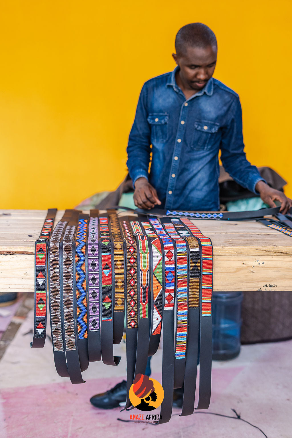 Artist working with patterned beaded leather belts at a workshop table